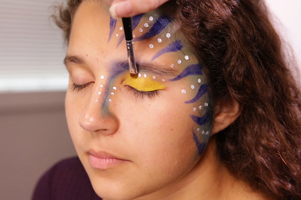 You apply more acrylic yellow paint to eyelids, step 7 of the Avatar Face Paint Tutorial.